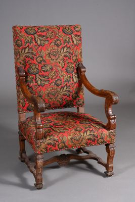 une vieille chaise dont l'assise est recouverte d'un tissu à motifs floraux rouges et verts
