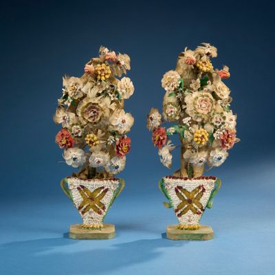une paire de vases en porcelaine contenant des fleurs, sur fond bleu