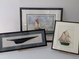 three framed pictures of sailboats on display on a table