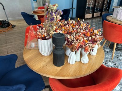 de nombreux vases remplis de fleurs posés sur une table dans une pièce
