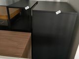 a black refrigerator in a small room with a mirror on the wall