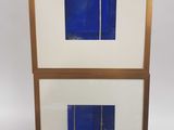 une paire de tableaux encadrés bleus et blancs posés sur un socle en bois