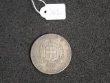 une pièce d'argent posée sur une surface noire, sur laquelle est apposée une étiquette de prix
