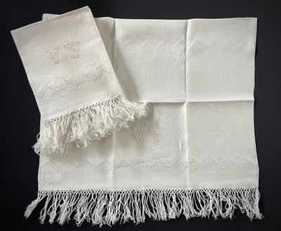 deux serviettes blanches à franges posées sur une surface noire