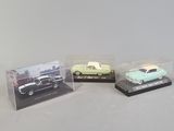 three miniature cars in plastic cases on a white surface