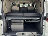 the back of a white van with its doors open and a table in the trunk
