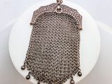 un gros plan d'un sac à main en cotte de mailles posé sur un gâteau blanc