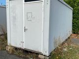 a white portable toilet sitting on the side of the road