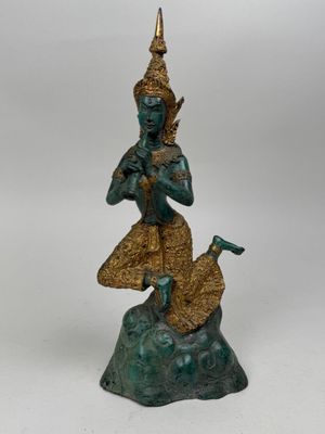 bronze statue of a person sitting on a rock with a bird in his hand
