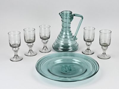 un pichet en verre et six verres à vin sur la table