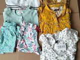 four baby clothes laid out on top of a cardboard box