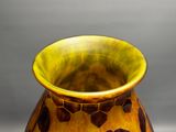 a yellow vase with brown spots on it on a table