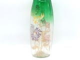 a green vase with flowers in it on a white surface
