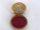 a close up of a gold locke with a red stone in it