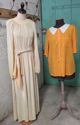 deux mannequins devant une porte verte et une robe posée sur un pied de mannequin