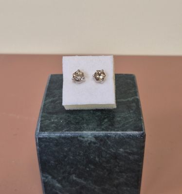 une paire de boucles d'oreilles à clous en diamant exposée sur un bloc de marbre