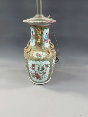 a vase with a chain on the handle and a lamp on the table