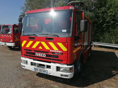 two fire trucks parked next to each other in the dirt