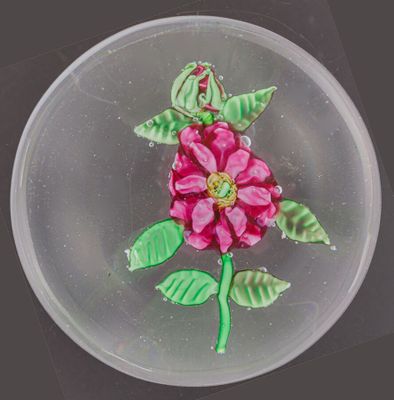une assiette en verre ornée d'une fleur, posée sur une table