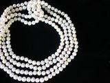 un gros plan sur un collier de perles blanches posé sur une surface noire
