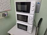 trois micro-ondes empilés les uns sur les autres sur une table