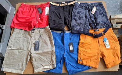 Plusieurs paires de shorts pour hommes sont posées sur une boîte en carton