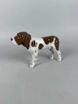 une figurine représentant un chien brun et blanc sur fond gris