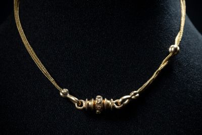 a close up of a gold necklace on a mannequin mannequin