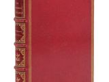 un vieux livre avec une couverture rouge et des bordures dorées sur fond blanc