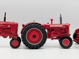 two red toy tractors sitting side by side on a white surface