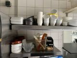 many plates and bowls on the shelves in the kitchen