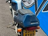 une moto bleue garée devant un bus bleu et blanc