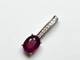 un gros plan d'un pendentif en rubis et diamants posé sur une surface blanche