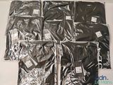 six bags of black t - shirts sitting on a table