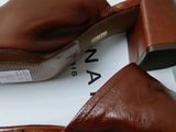 an image of a pair of brown leather mules on a white box