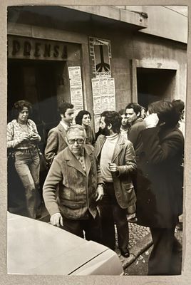 photographie en noir et blanc d'un groupe de personnes debout devant un bâtiment