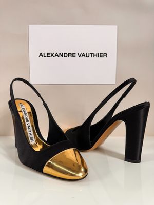 a pair of black and gold shoes on a white table