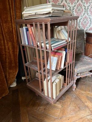 une bibliothèque sur laquelle sont posés des livres, dans un coin de la pièce