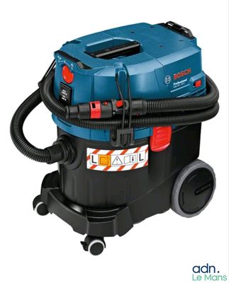 un aspirateur bleu et noir muni d'un tuyau, sur fond blanc