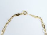a close up of a gold necklace with a chain on a white background