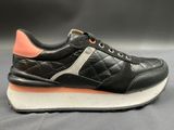 the black and orange sneakers are lined up on a gray surface
