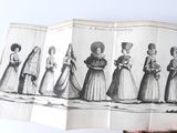 a person holding an open book with a drawing of women in dresses