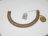Gros plan sur un bracelet en or orné d'une pièce de monnaie