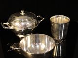 two silver dishes and a cup on a black surface