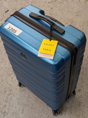 une valise bleue avec une étiquette, posée par terre