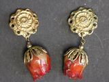 pair of red and gold earrings on a black surface