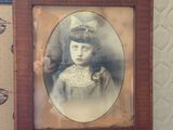 une vieille photo d'une petite fille assise sur une chaise