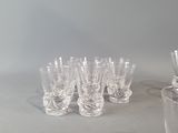 bottles and glasses are lined up on a table in front of a gray wall
