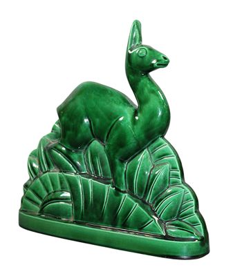 figurine en céramique représentant un cerf posé sur un socle feuillu