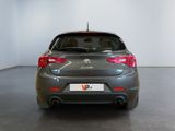 the back end of a grey car in a room with a white wall